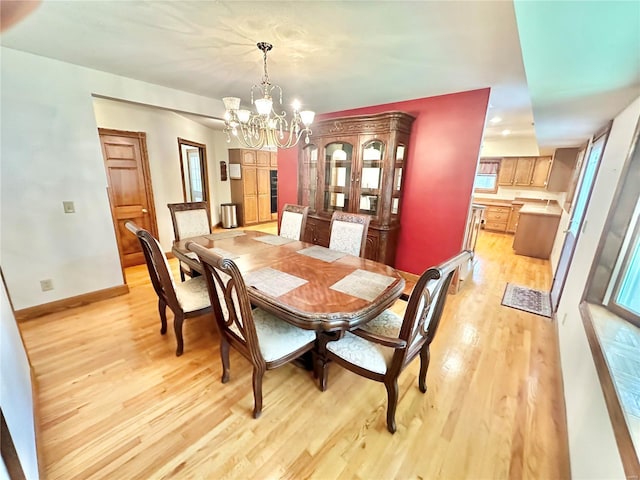 dining space featuring baseboards, light wood finished floors, and a notable chandelier