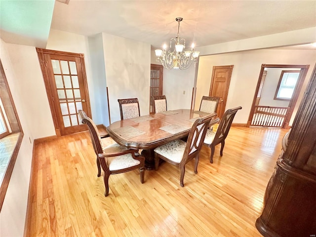 dining space with light wood-style flooring, baseboards, and a notable chandelier