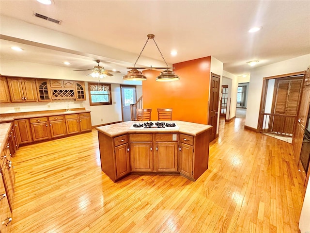 kitchen with brown cabinetry, white gas stovetop, light countertops, and light wood finished floors