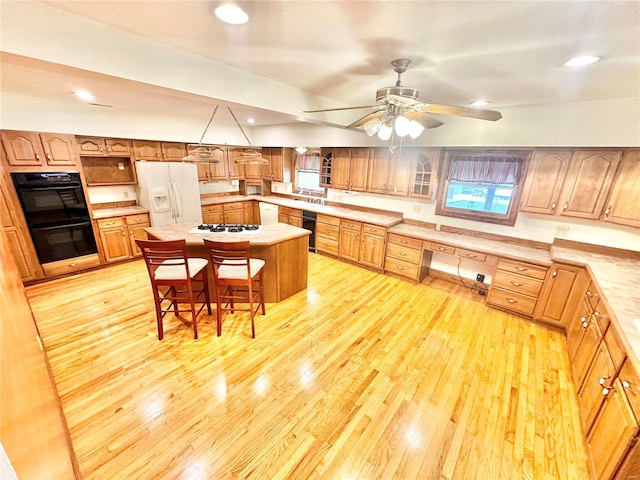 kitchen with a breakfast bar area, white appliances, light wood-style floors, light countertops, and built in desk