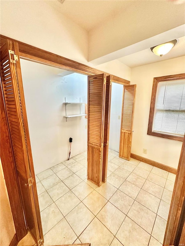 hallway with light tile patterned flooring and baseboards