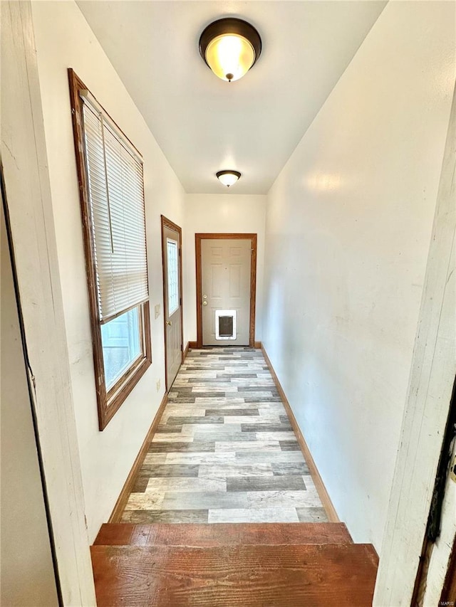 corridor featuring light wood-style floors and baseboards