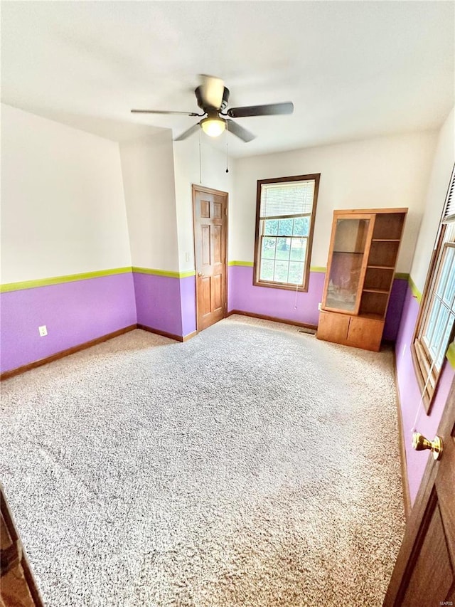 carpeted spare room with a ceiling fan, visible vents, and baseboards