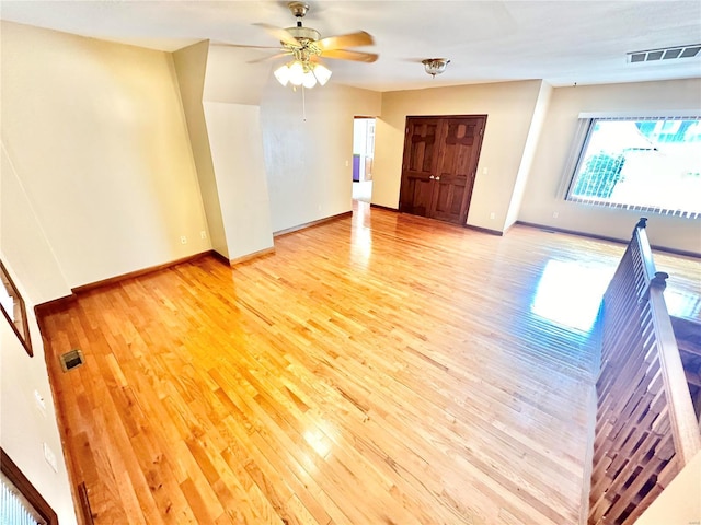 unfurnished room with light wood-type flooring, visible vents, ceiling fan, and baseboards