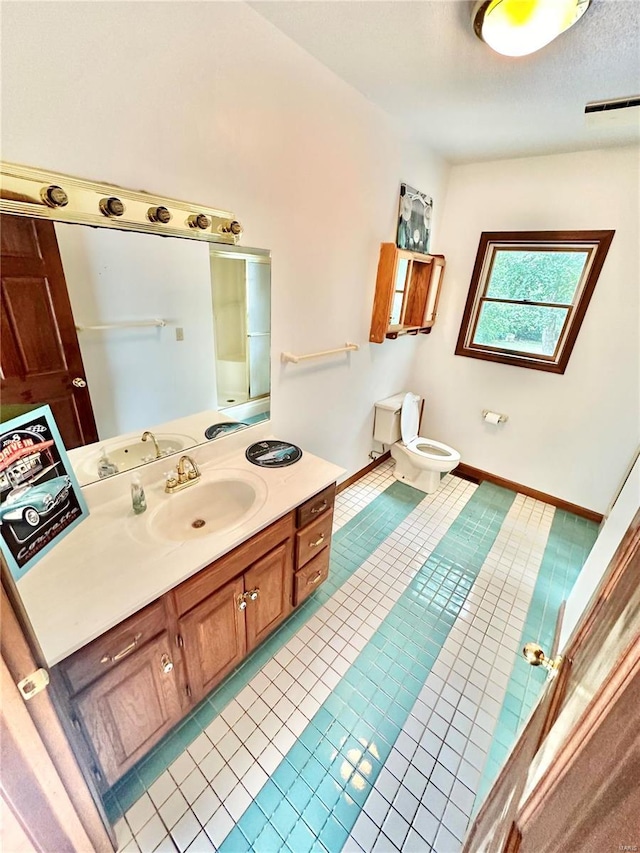 bathroom featuring visible vents, toilet, vanity, tile patterned flooring, and baseboards