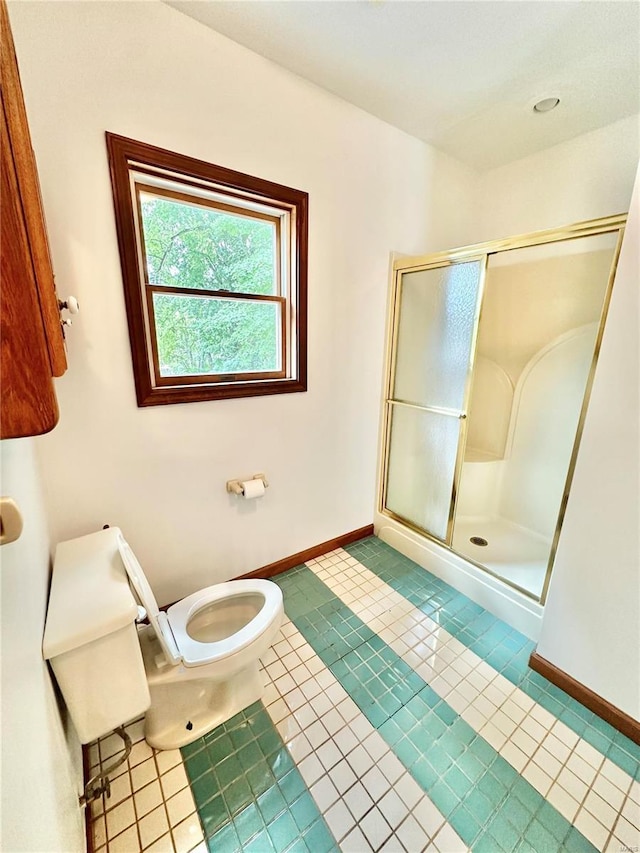 bathroom with a stall shower, tile patterned floors, toilet, and baseboards