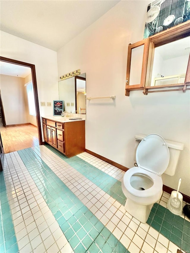 bathroom featuring toilet, tile patterned flooring, vanity, and baseboards