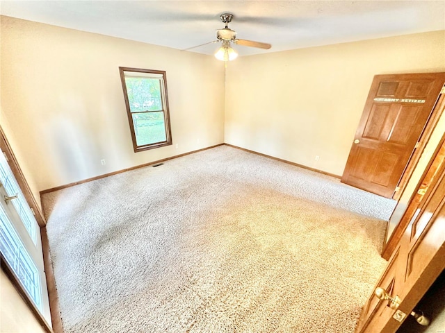 unfurnished room featuring a ceiling fan, light colored carpet, visible vents, and baseboards