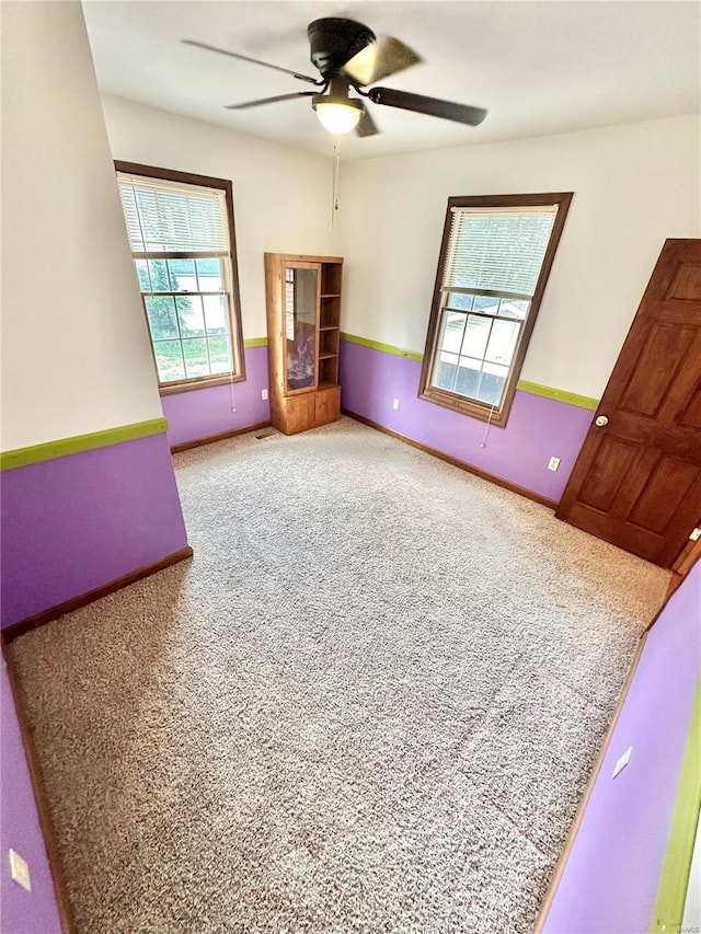 carpeted empty room featuring ceiling fan and baseboards