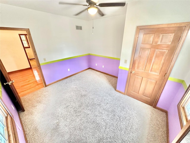 unfurnished room featuring ceiling fan, carpet flooring, visible vents, and baseboards