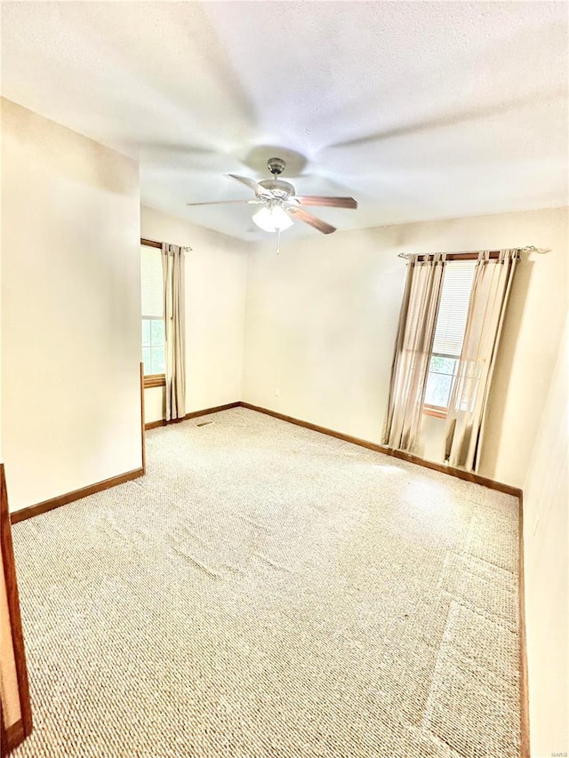 carpeted empty room with a ceiling fan, a textured ceiling, and baseboards