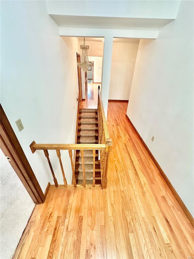 staircase featuring a notable chandelier, baseboards, and wood finished floors