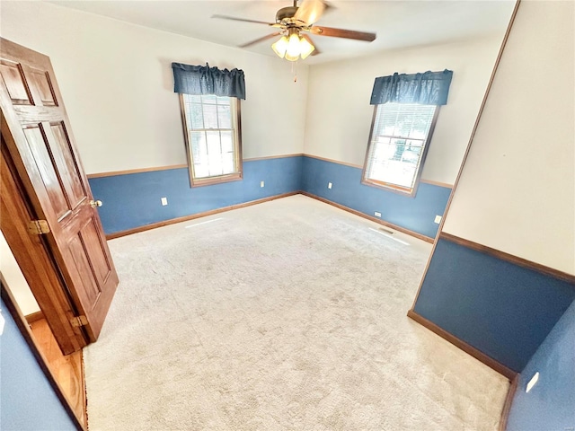 spare room with a ceiling fan, carpet, visible vents, and baseboards