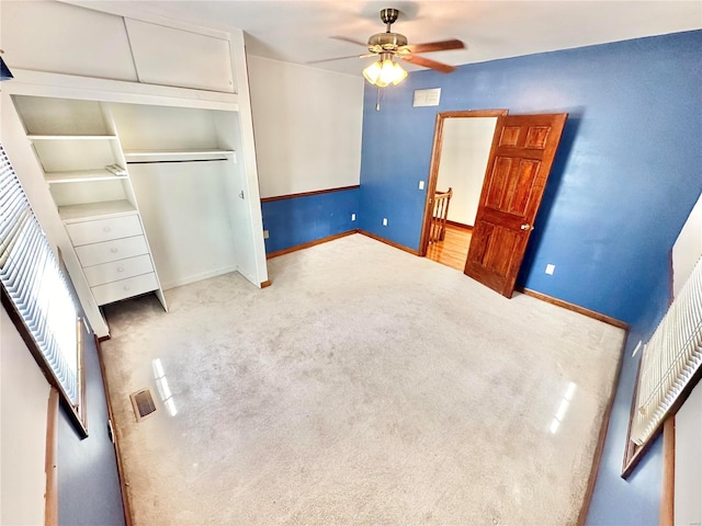 unfurnished bedroom with carpet floors, a closet, baseboards, and a ceiling fan