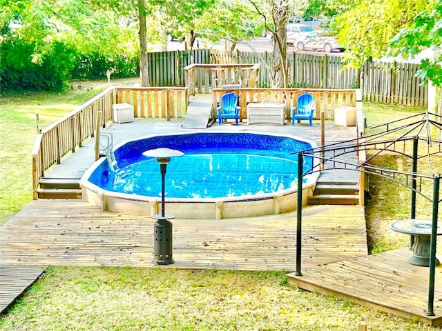 outdoor pool with a yard, fence, and a wooden deck