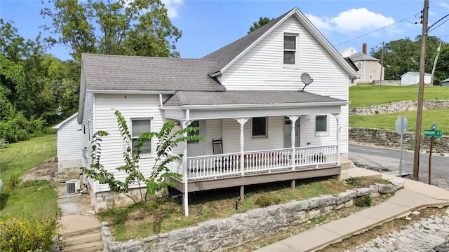 view of front of home with a front lawn, central AC unit, and a porch