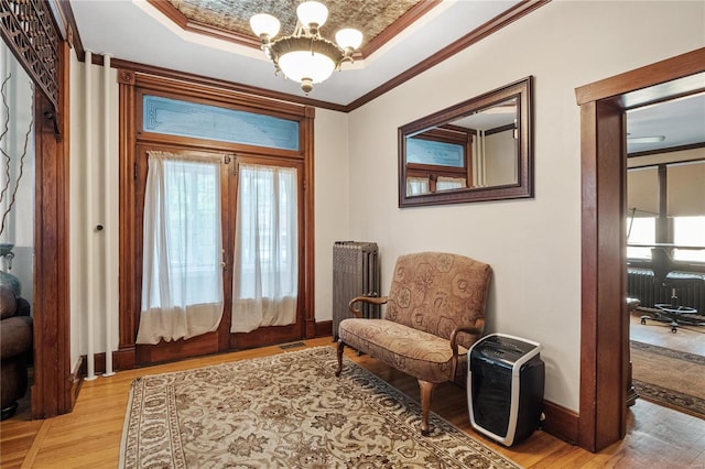 sitting room with radiator, french doors, crown molding, a chandelier, and light hardwood / wood-style floors