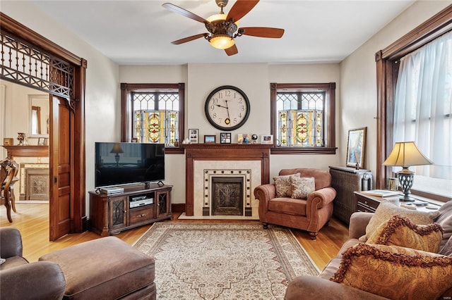 living room with ceiling fan, radiator, a tile fireplace, and light hardwood / wood-style flooring