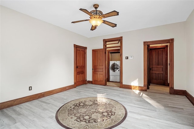 bedroom with independent washer and dryer, light wood-type flooring, and ceiling fan