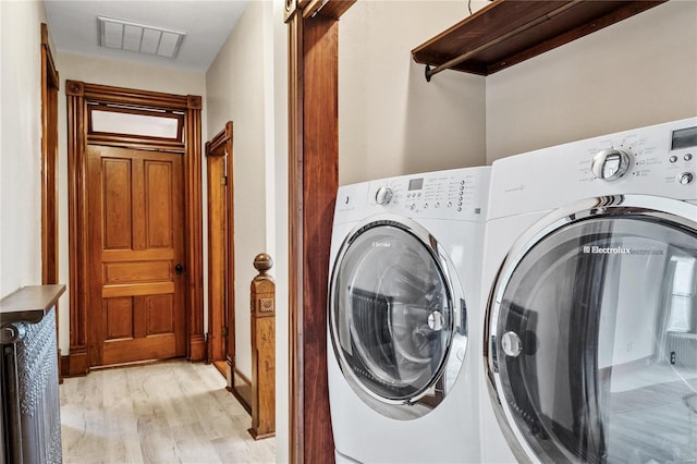 laundry area with independent washer and dryer and light hardwood / wood-style flooring