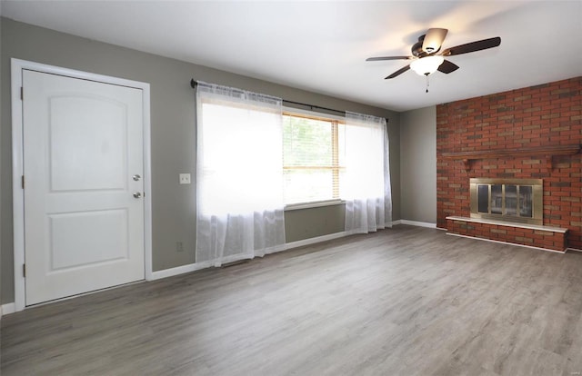 unfurnished living room featuring hardwood / wood-style floors, ceiling fan, and a fireplace