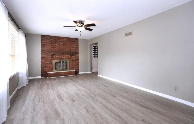 unfurnished living room featuring light wood-type flooring, ceiling fan, and a fireplace