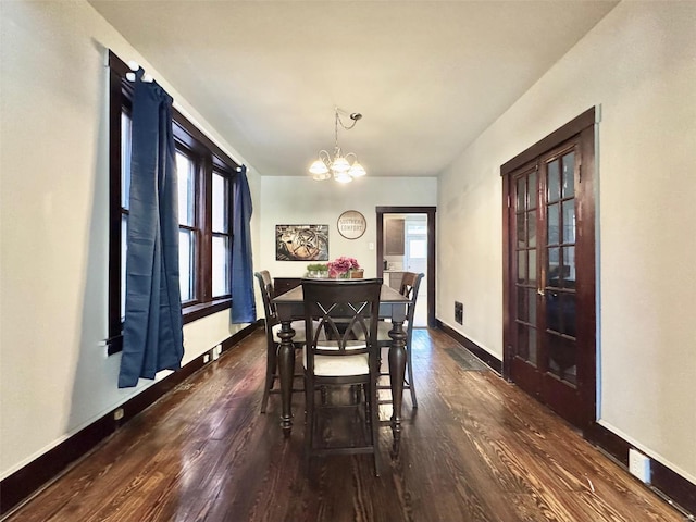 dining area with dark wood-type flooring, a notable chandelier, and plenty of natural light