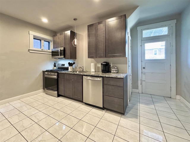 kitchen featuring dark brown cabinets, hanging light fixtures, light stone countertops, sink, and stainless steel appliances