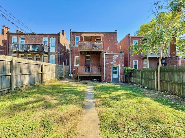 back of house featuring a yard and a balcony