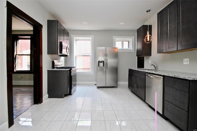 kitchen with hanging light fixtures, light stone countertops, sink, light hardwood / wood-style floors, and stainless steel appliances