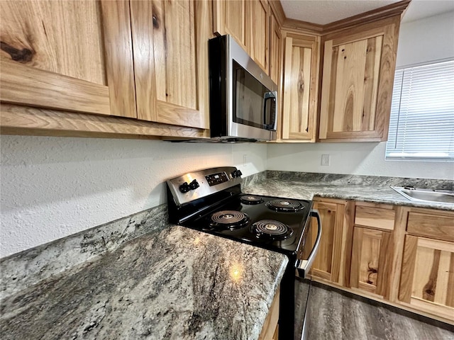 kitchen with stainless steel appliances, dark hardwood / wood-style floors, dark stone counters, and sink