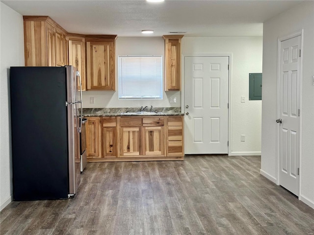 kitchen featuring hardwood / wood-style floors, sink, stainless steel refrigerator, and light stone countertops