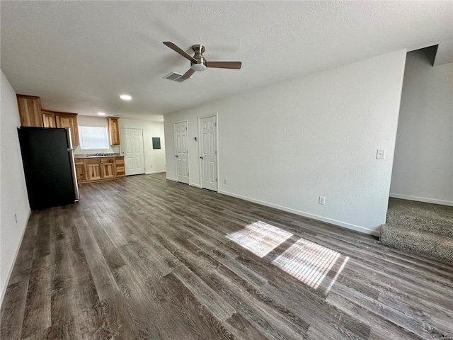 unfurnished living room featuring dark hardwood / wood-style flooring, a textured ceiling, and ceiling fan