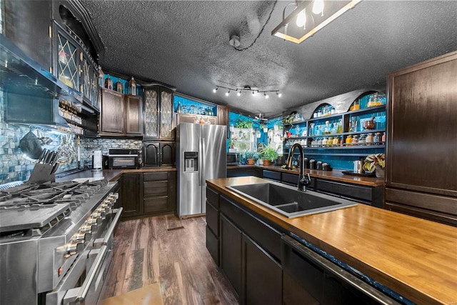 kitchen featuring a textured ceiling, stainless steel appliances, dark wood-style flooring, a sink, and wood counters