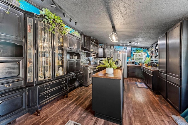 kitchen with stainless steel appliances, wood counters, a textured ceiling, and dark wood-style floors