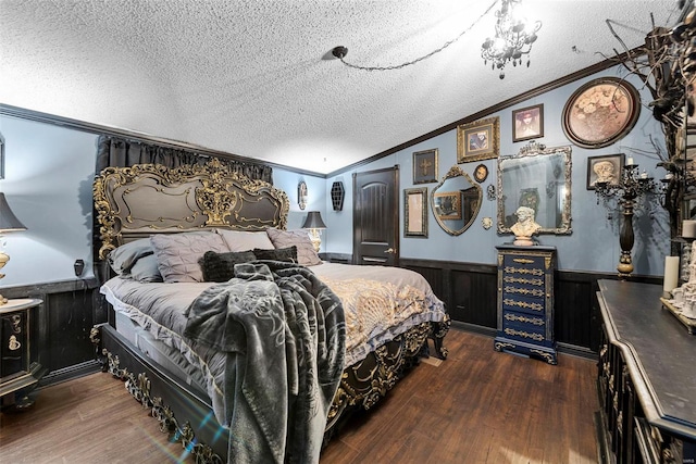 bedroom featuring a wainscoted wall, ornamental molding, wood finished floors, vaulted ceiling, and a textured ceiling