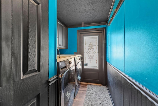 laundry room featuring crown molding, cabinet space, wainscoting, a textured ceiling, and independent washer and dryer