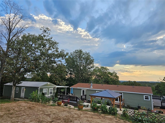 back of house at dusk featuring a deck and a gazebo