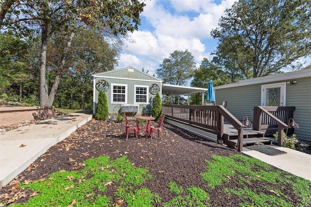 exterior space featuring a deck, an attached carport, and an outdoor structure