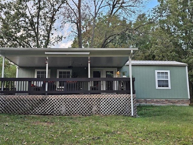 rear view of house featuring metal roof, a yard, and a wooden deck