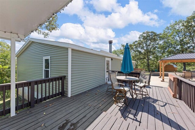 wooden deck featuring outdoor dining space and a gazebo