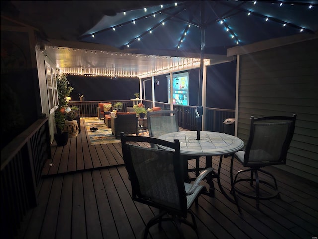 deck at night featuring outdoor dining area