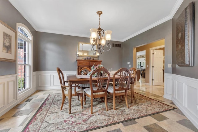 dining space with ornamental molding, wainscoting, visible vents, and a notable chandelier