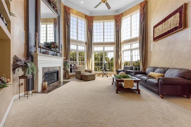 living room with baseboards, a premium fireplace, ornamental molding, a high ceiling, and carpet flooring