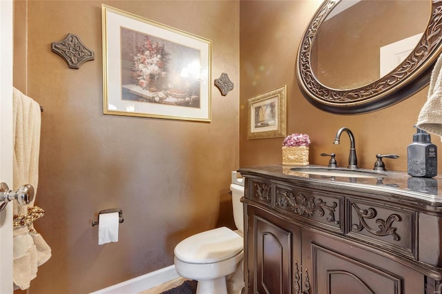 bathroom featuring baseboards, vanity, and toilet