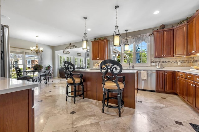 kitchen with light countertops, hanging light fixtures, decorative backsplash, dishwasher, and a kitchen breakfast bar