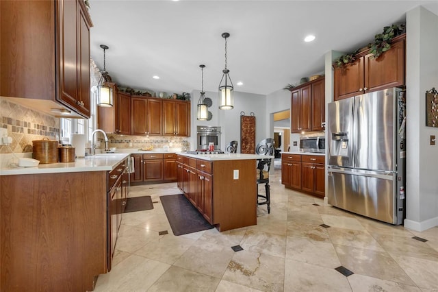 kitchen with appliances with stainless steel finishes, light countertops, a sink, and a center island