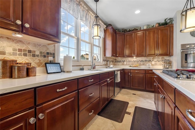 kitchen with decorative light fixtures, stainless steel appliances, light countertops, backsplash, and a sink