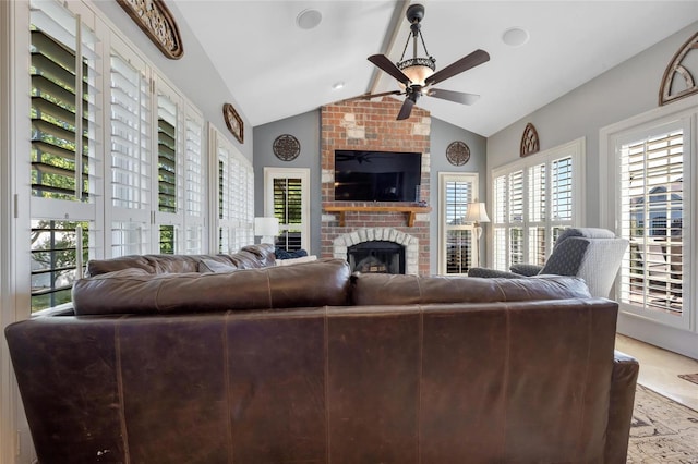 living room with a brick fireplace, vaulted ceiling, and ceiling fan