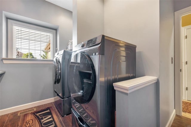 clothes washing area featuring visible vents, dark wood finished floors, baseboards, and washing machine and clothes dryer